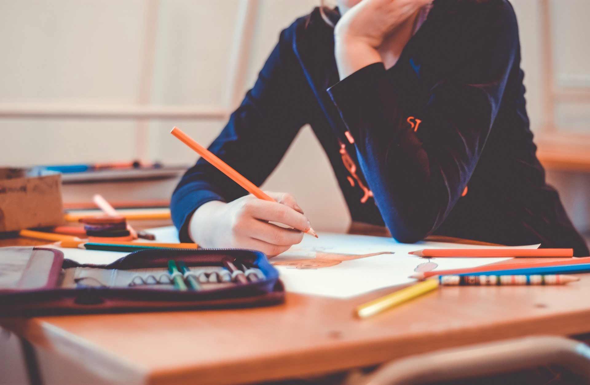 a person drawing with with an orange pencil